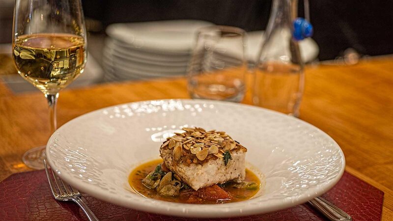 Tuna entree topped with crushed nuts on top of vegetables